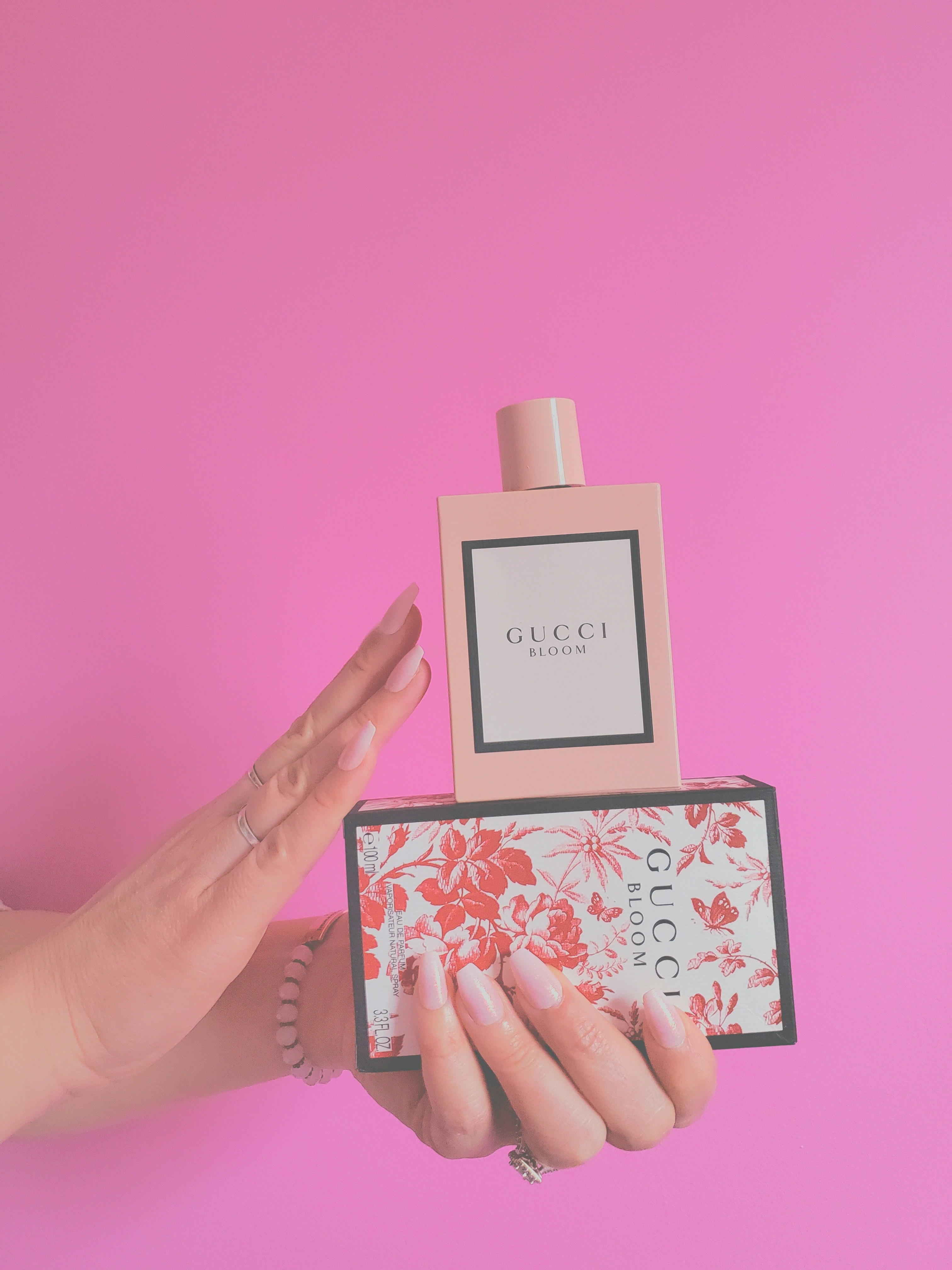 a woman's hand holding a box with a bottle of gucci