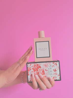 a woman's hand holding a box with a bottle of gucci