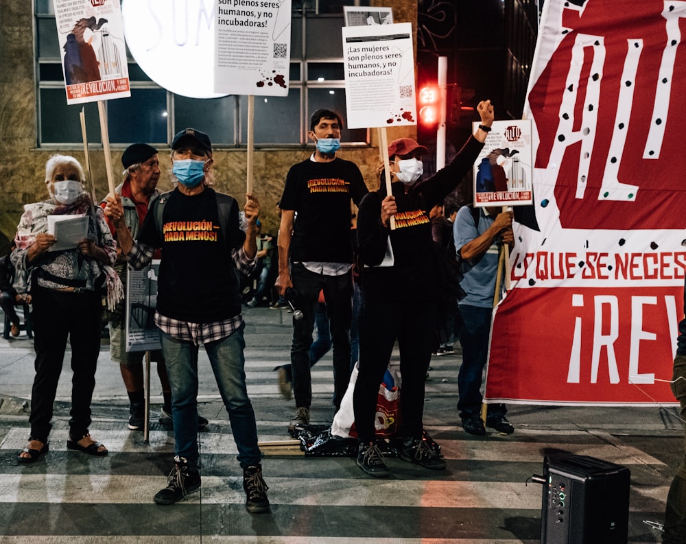 a group of people standing around each other holding signs