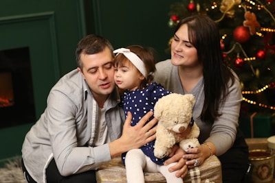 a man, woman and child sitting in front of a christmas tree