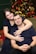a man and a woman hugging in front of a christmas tree