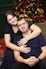 a man and a woman hugging in front of a christmas tree