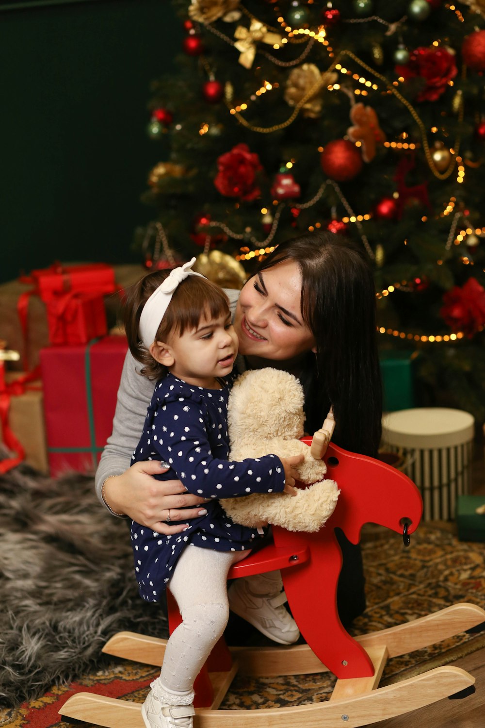 a woman holding a child in front of a christmas tree
