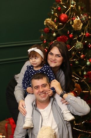A family posing in front of a beautifully lit Christmas tree.