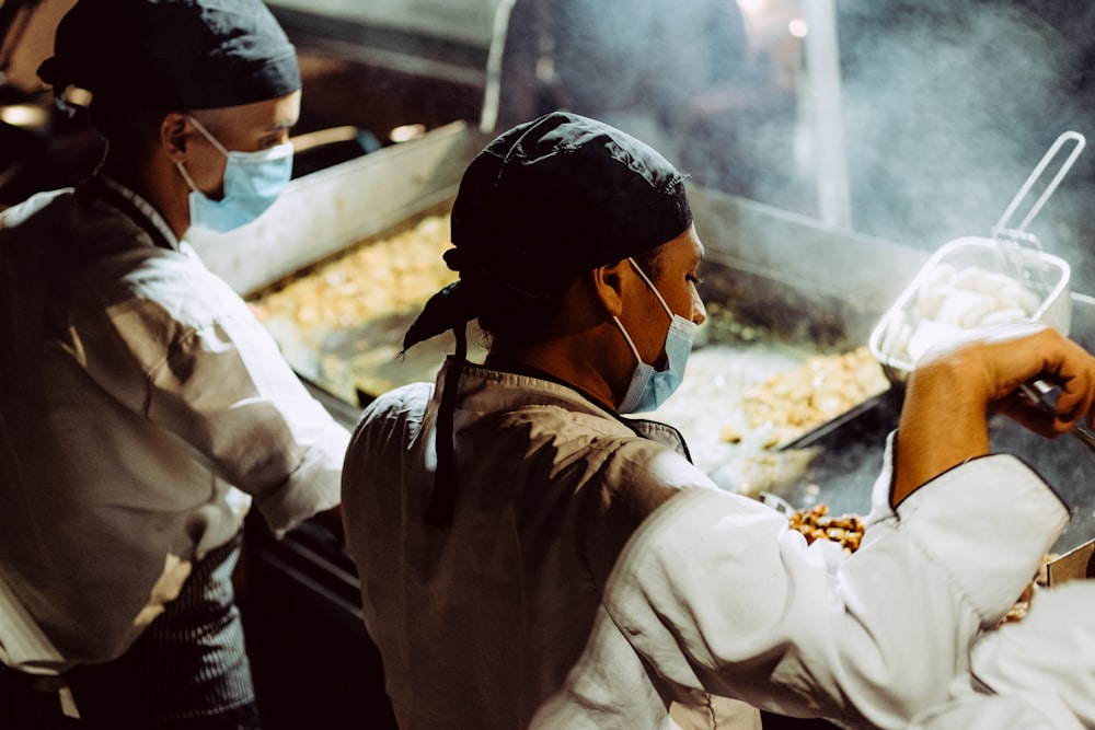 a man and a woman cooking food in a kitchen