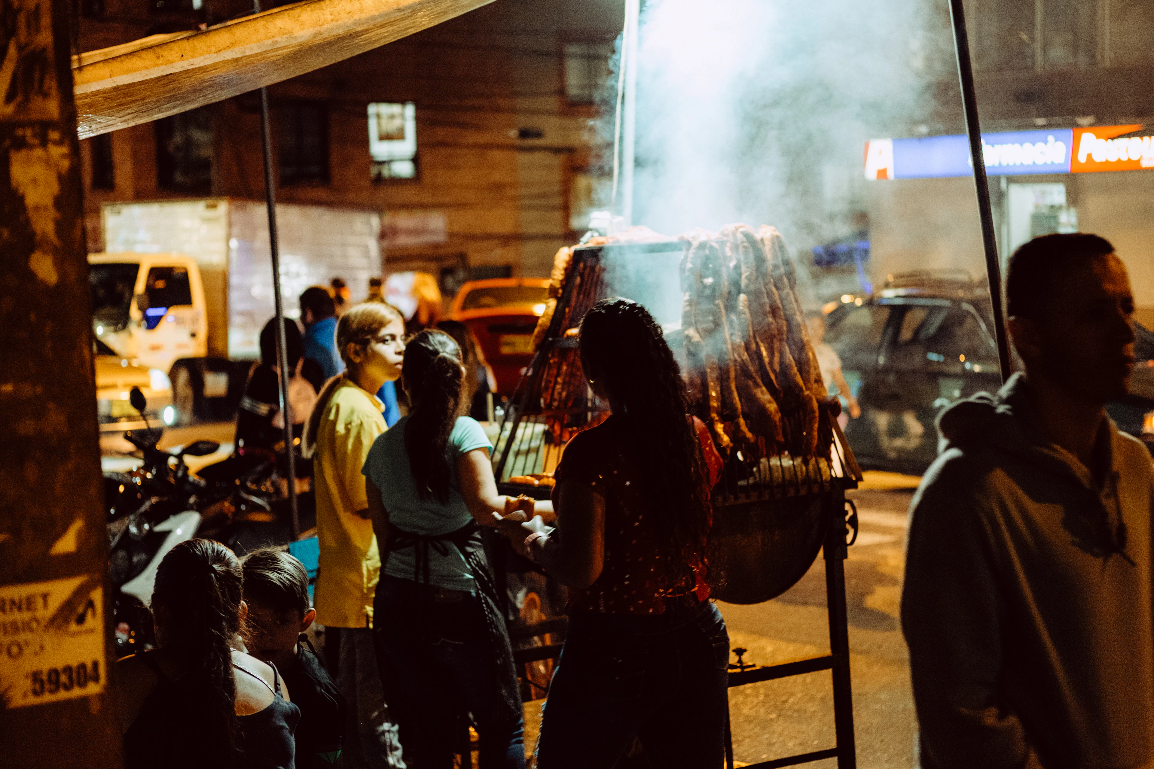 A street food stall in Medellin at night, steam rising over the griddle