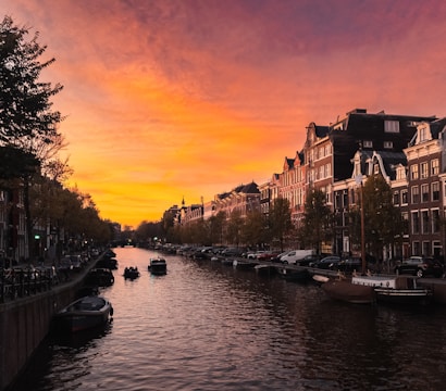 A panoramic view of Amsterdam's canals lined with colorful historic houses at sunset.