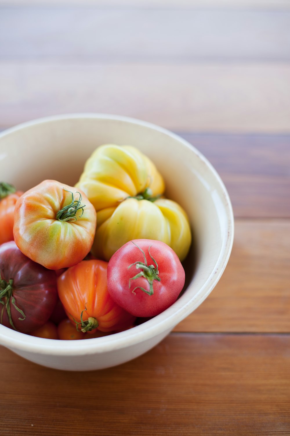 a bowl of tomatoes on a wooden table