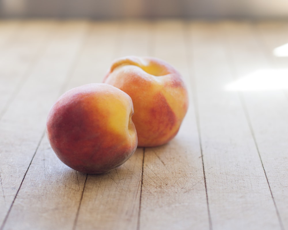 a couple of peaches sitting on top of a wooden floor