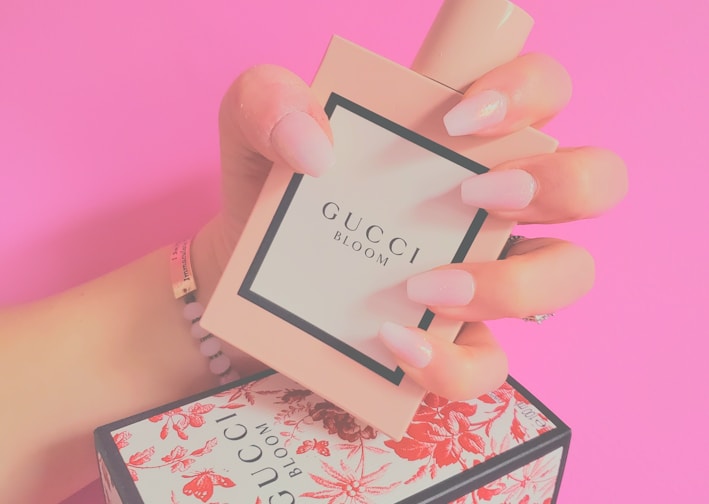 a woman's hand holding a small box with a perfume