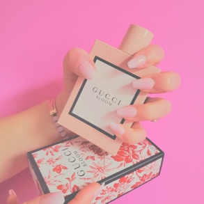 a woman's hand holding a small box with a perfume