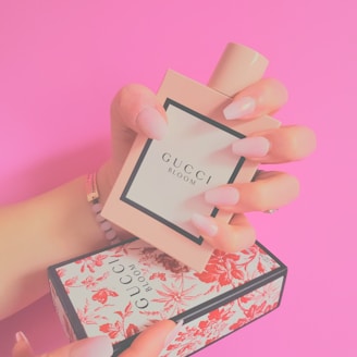 a woman's hand holding a small box with a perfume