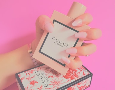 a woman's hand holding a small box with a perfume
