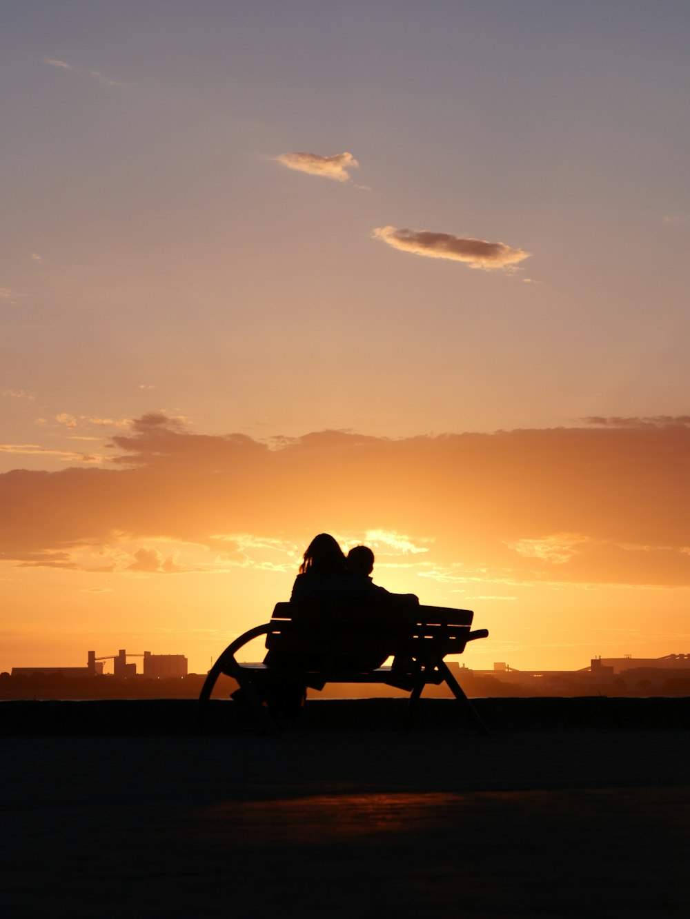 a person sitting on a bench at sunset
