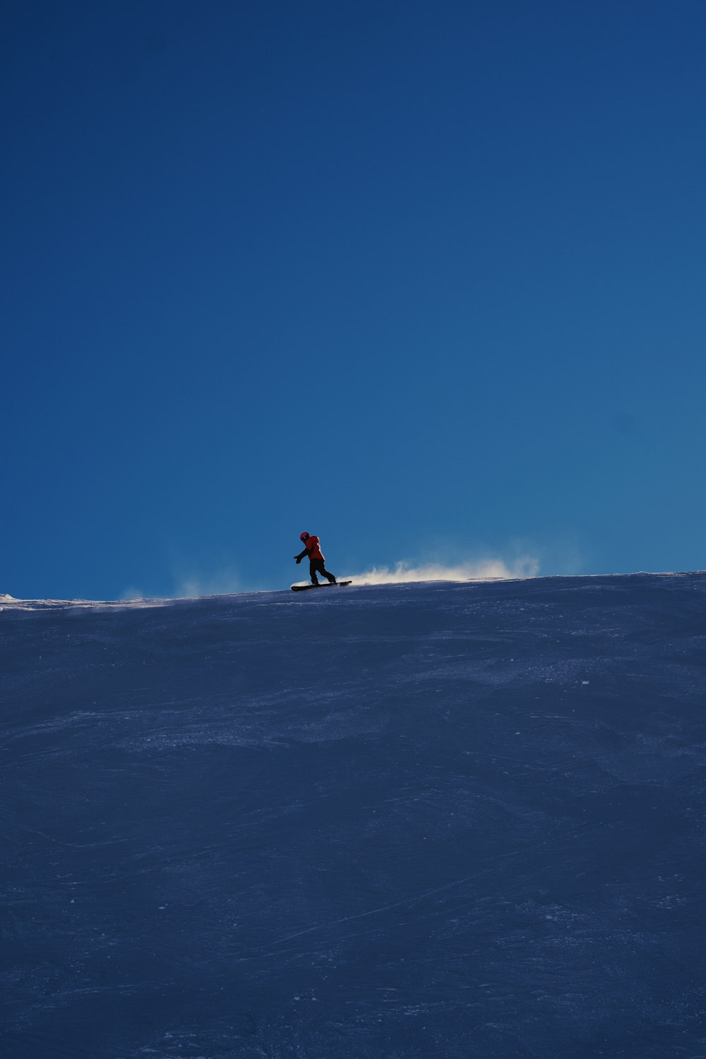 a person riding a snowboard down a snow covered slope