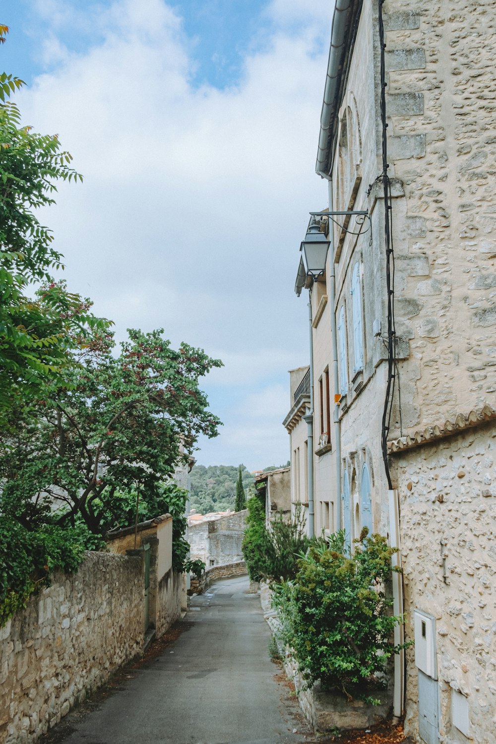 a narrow street with a stone building on the side