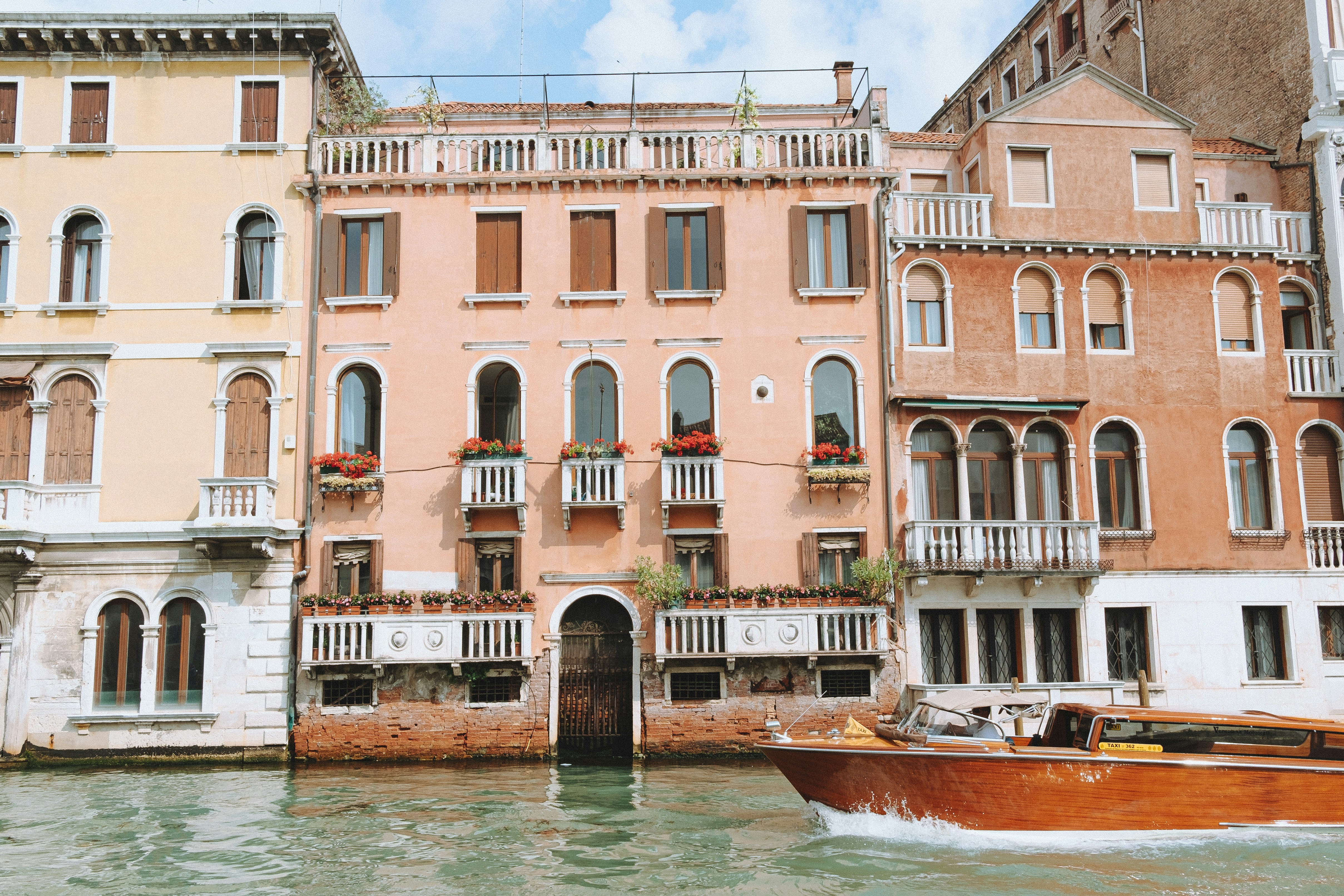 A boat traveling down a river next to tall buildings