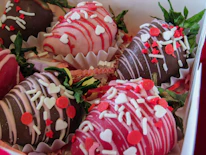 Close-up of heart-shaped strawberries and rich chocolate truffles arranged with pink decorations.