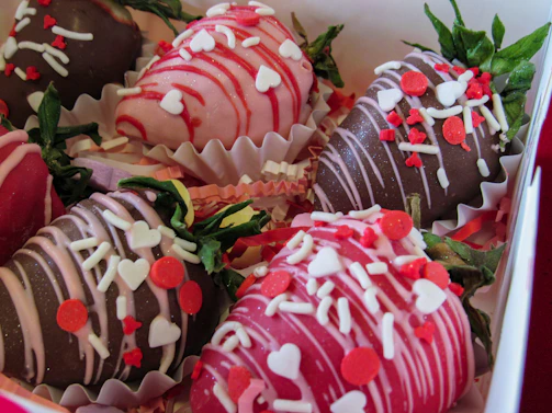 Close-up of chocolate-dipped strawberries with colorful sprinkles arranged on a rustic wooden platter.