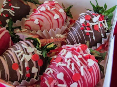 Close-up of heart-shaped strawberries and rich chocolate truffles arranged with pink decorations.