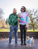 Two dogs in matching stylish hoodies enjoying a walk in the park with autumn leaves.