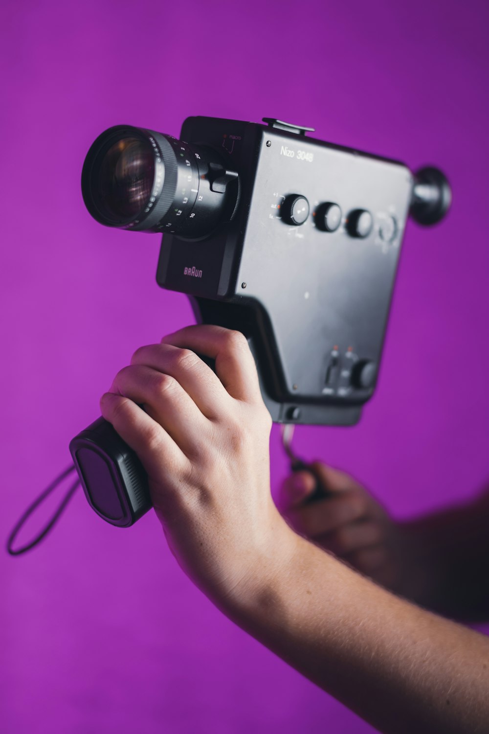 a person holding a camera with a purple background