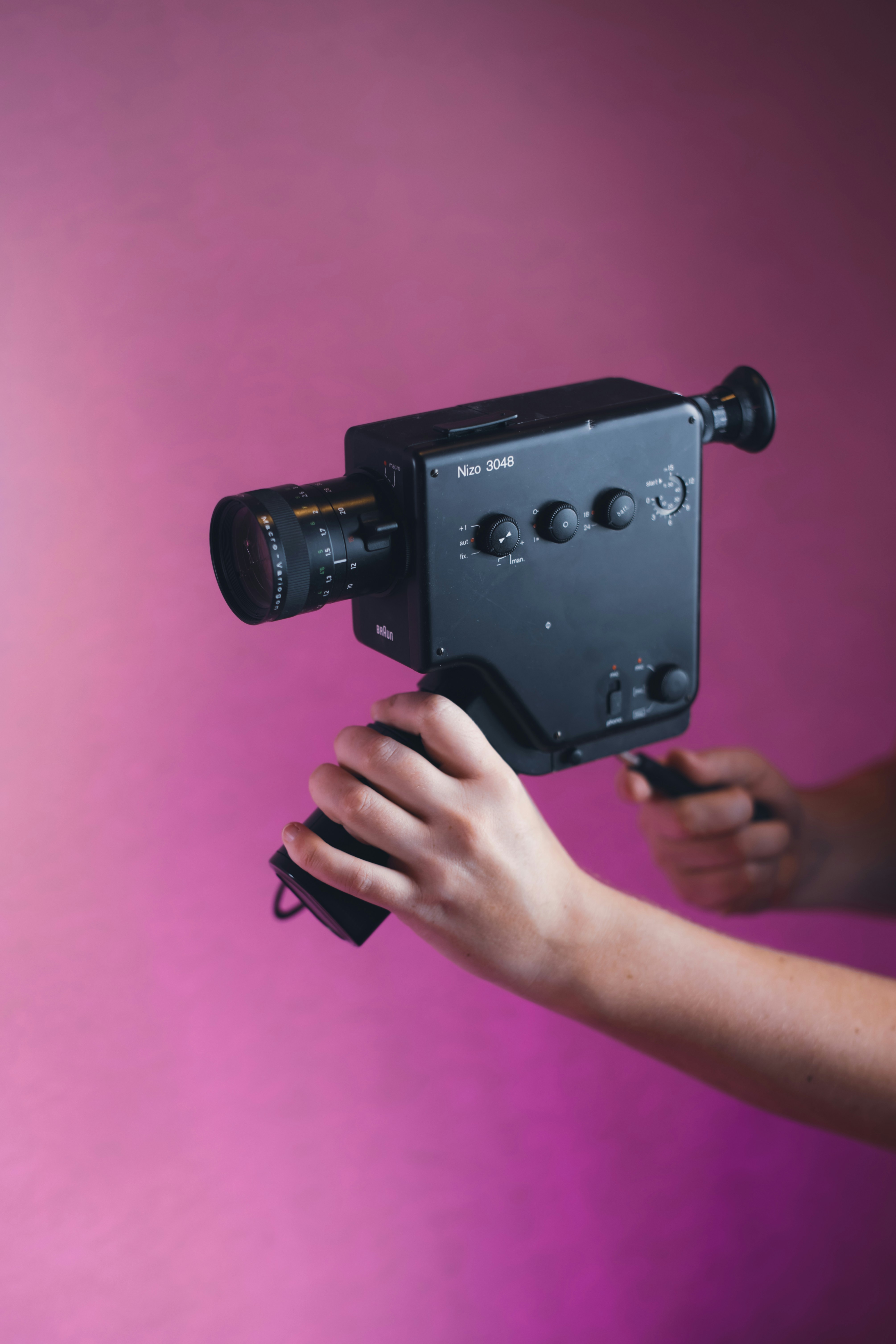 Eine Person, die eine Kamera mit rosa Hintergrund hält