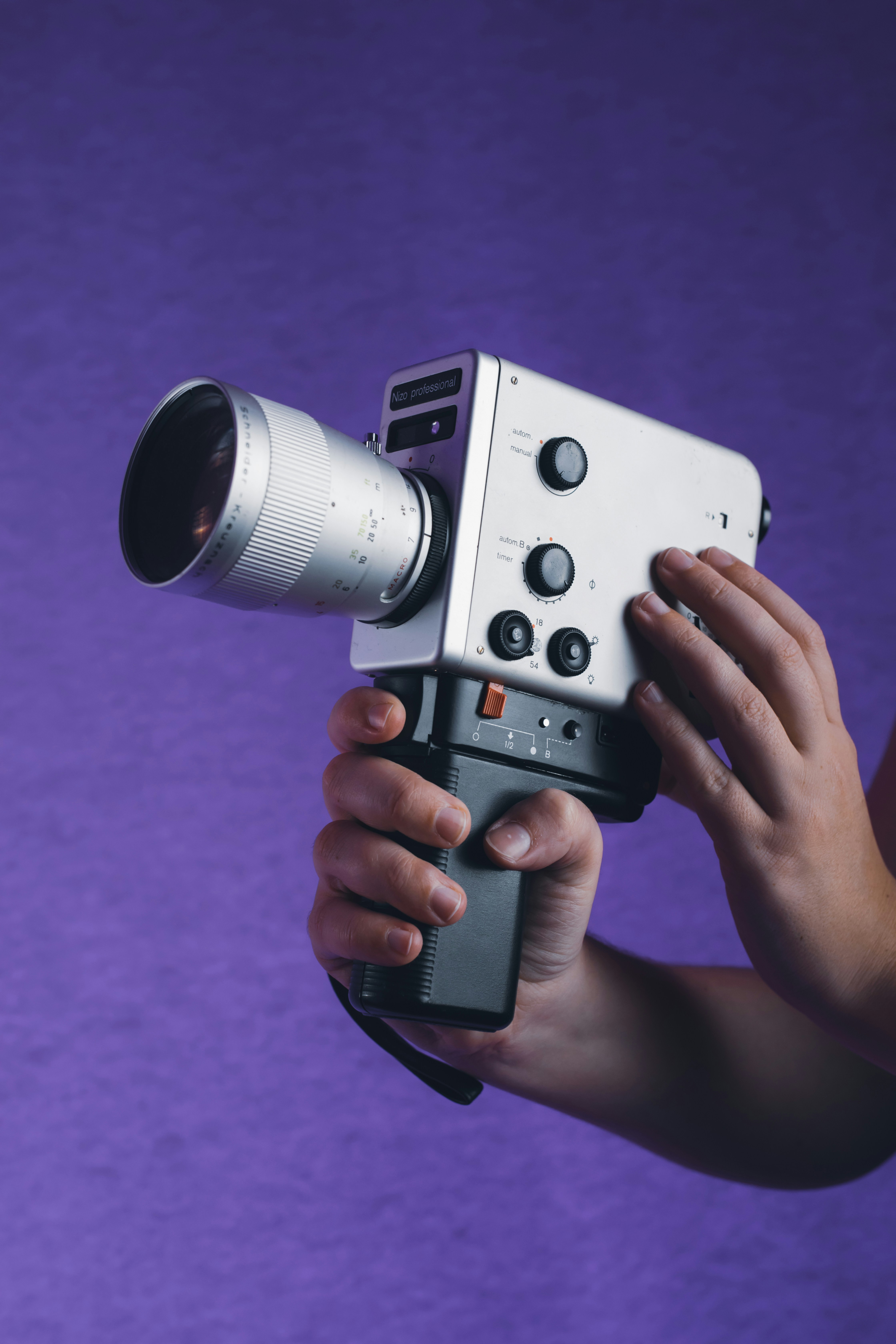 eine Person, die eine Kamera mit einem daran befestigten Objektiv hält