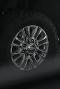 Close-up of a shiny metallic SUV wheel on rugged terrain.