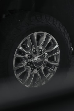 Close-up of a shiny metallic SUV wheel on rugged terrain.