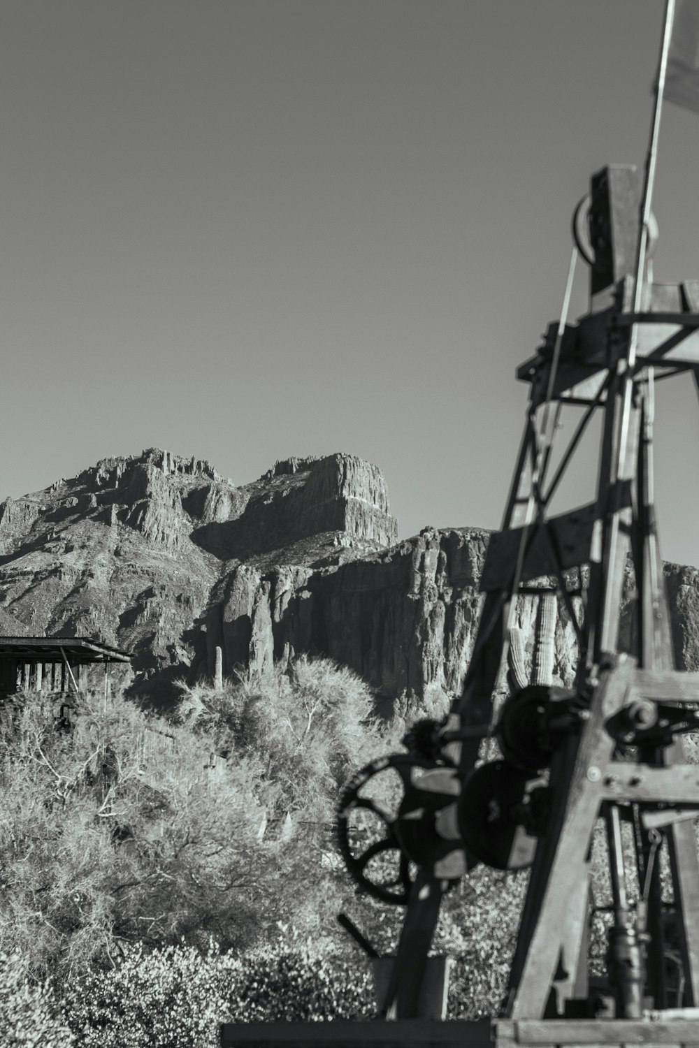 a black and white photo of a windmill and mountains