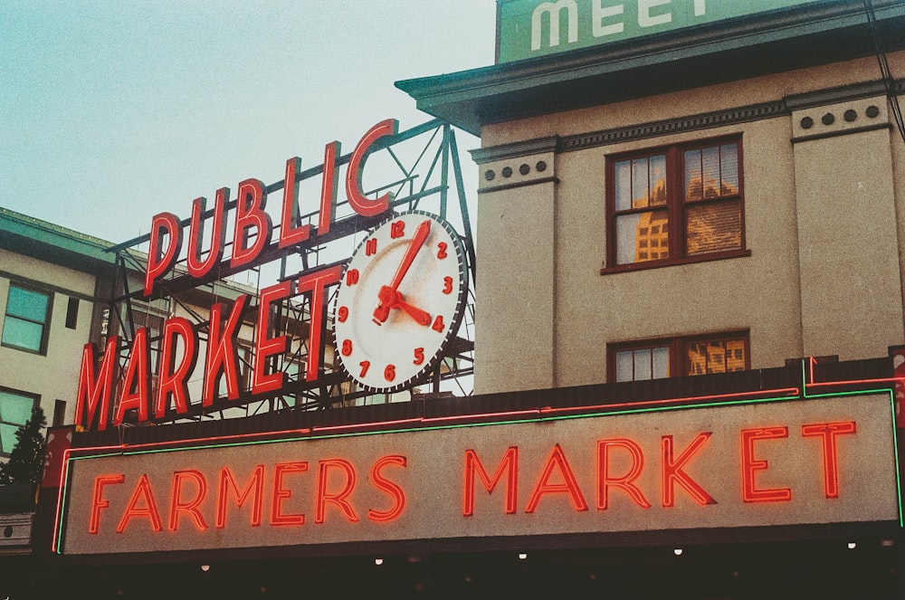 a sign for a farmers market with a clock on top