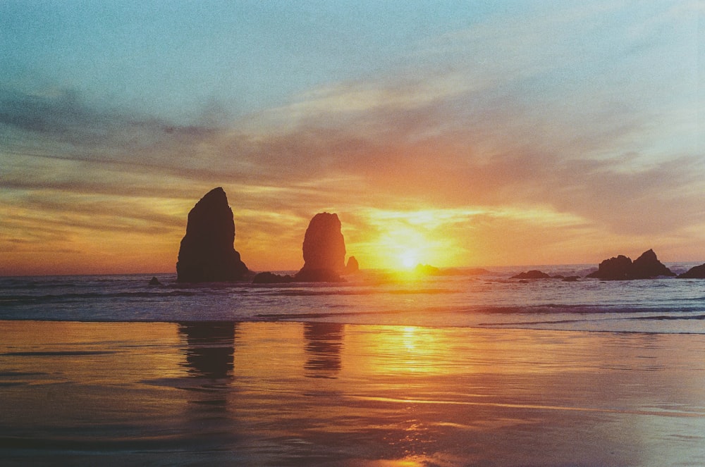 El sol se está poniendo sobre el océano con rocas en el agua
