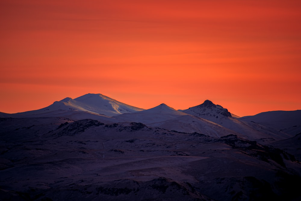 a mountain range with a red sky in the background