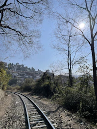 Scenic countryside railway track with charming countryside inns in the background under a blue sky.