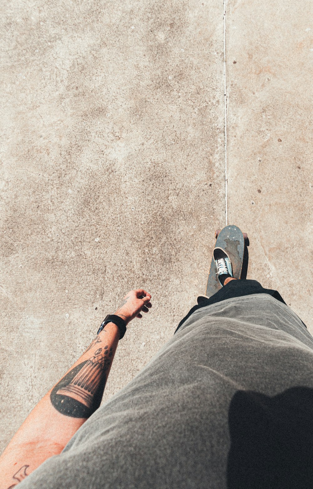 a man with a skateboard standing on a sidewalk