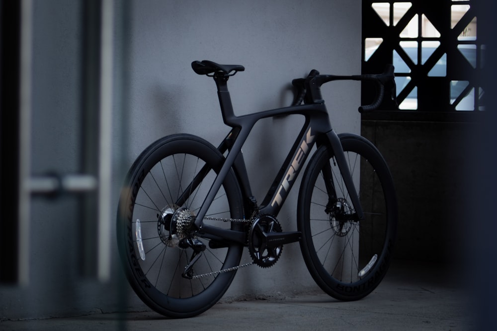 a black bike is leaning against a wall