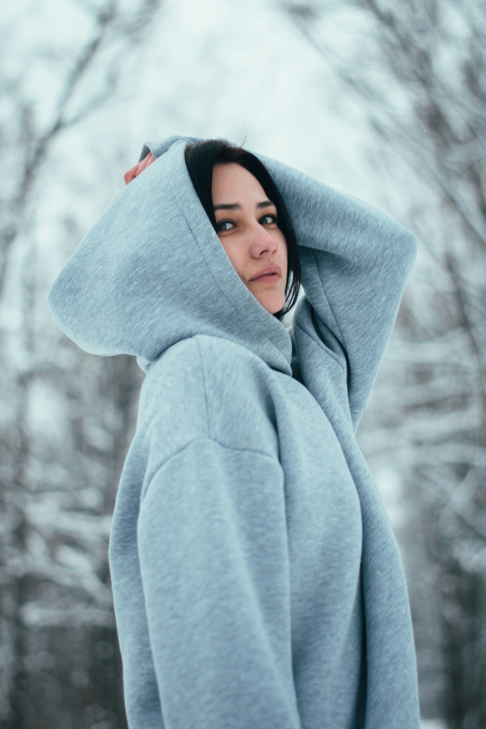 a woman in a blue hoodie standing in the snow