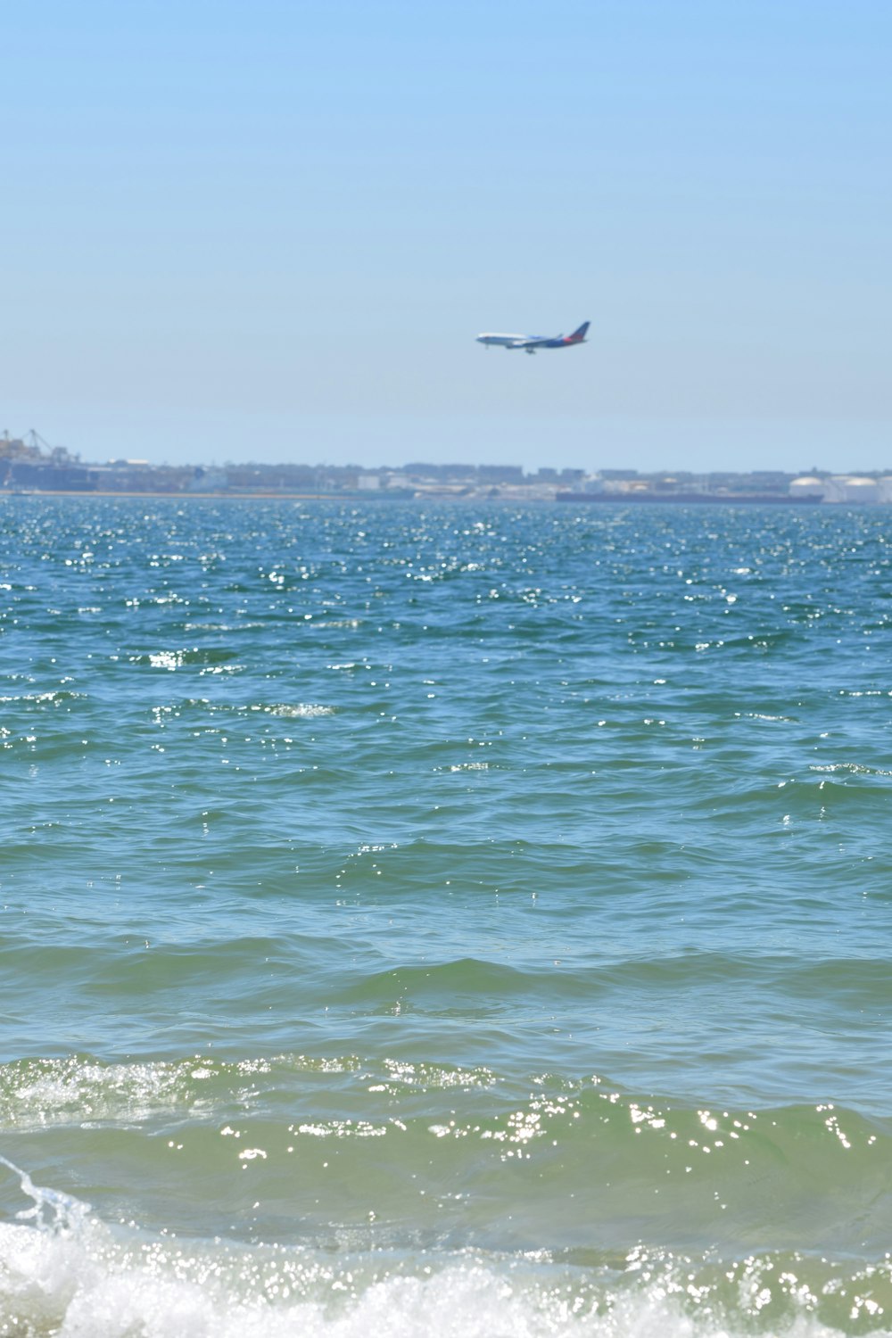 a large jetliner flying over a large body of water