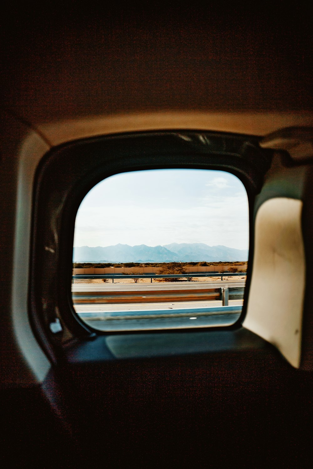 a rear view mirror of a car with mountains in the background