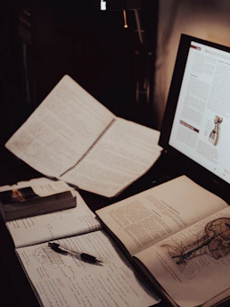 Reading an article on a laptop and notes taken from it on a notebook.