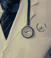 White lab coat with company logo embroidered on the chest pocket, displayed on a mannequin.