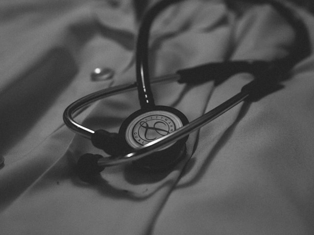 A close-up of a medical journal open on a desk with a stethoscope and pen nearby