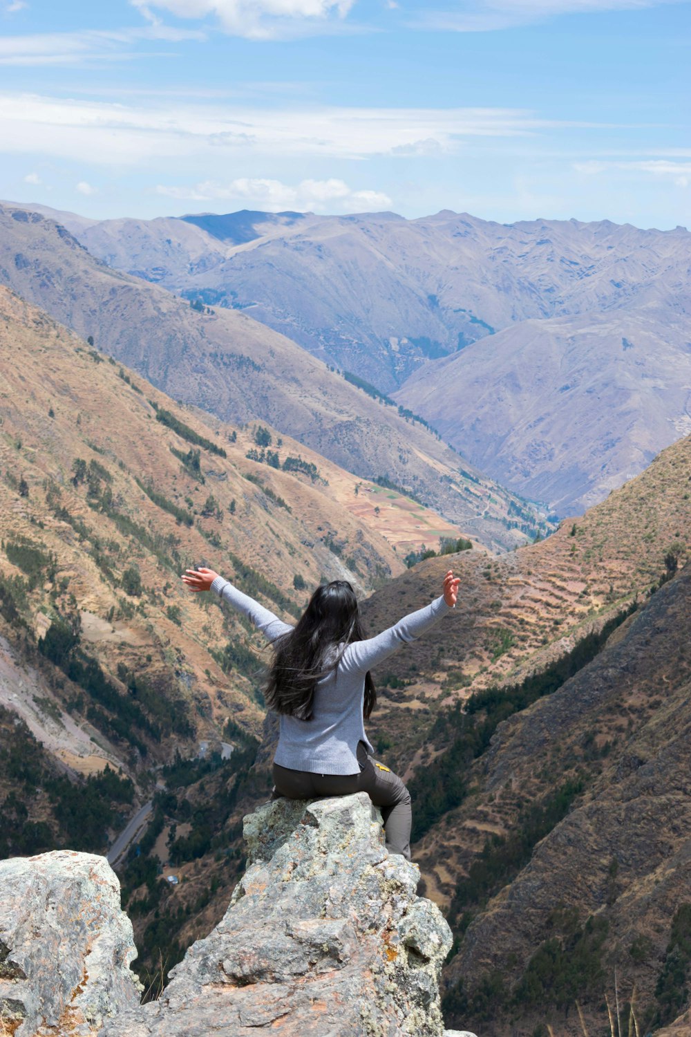 a woman sitting on top of a large rock