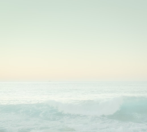 A serene coaching session by the ocean with light blues and soft pinks in the background.