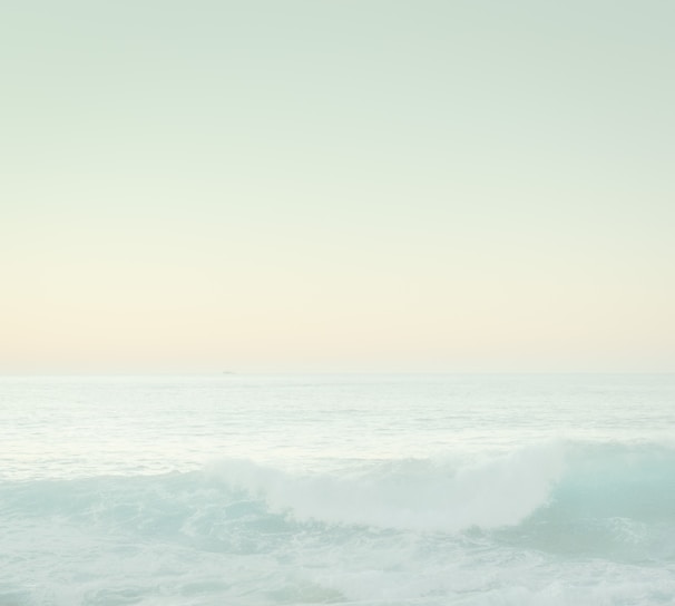 Soft pastel watercolor background with gentle waves blending into a serene sky.