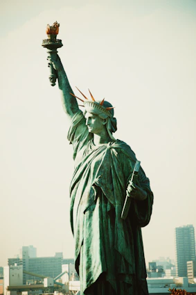 Statue of the blindfolded Roman goddess of justice standing tall with the Andes mountains in the background at sunset.