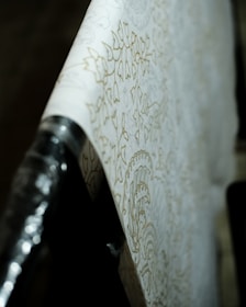 Close-up of textured wallpaper in warm off-white tones highlighting delicate patterns and soft lighting.