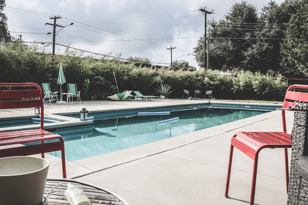 a pool with chairs and a table next to it