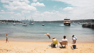 a group of people sitting on top of a sandy beach